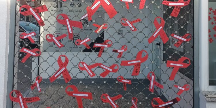 40 lazos rojos con mensajes en la puerta de la sede de Cruz Roja Santa Marta invitan a reflexionar sobre el estigma social que aún sufren los enfermos de Sida